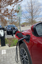 Red car plugged into a non-metered charging station at Switchyard Park in April 2024