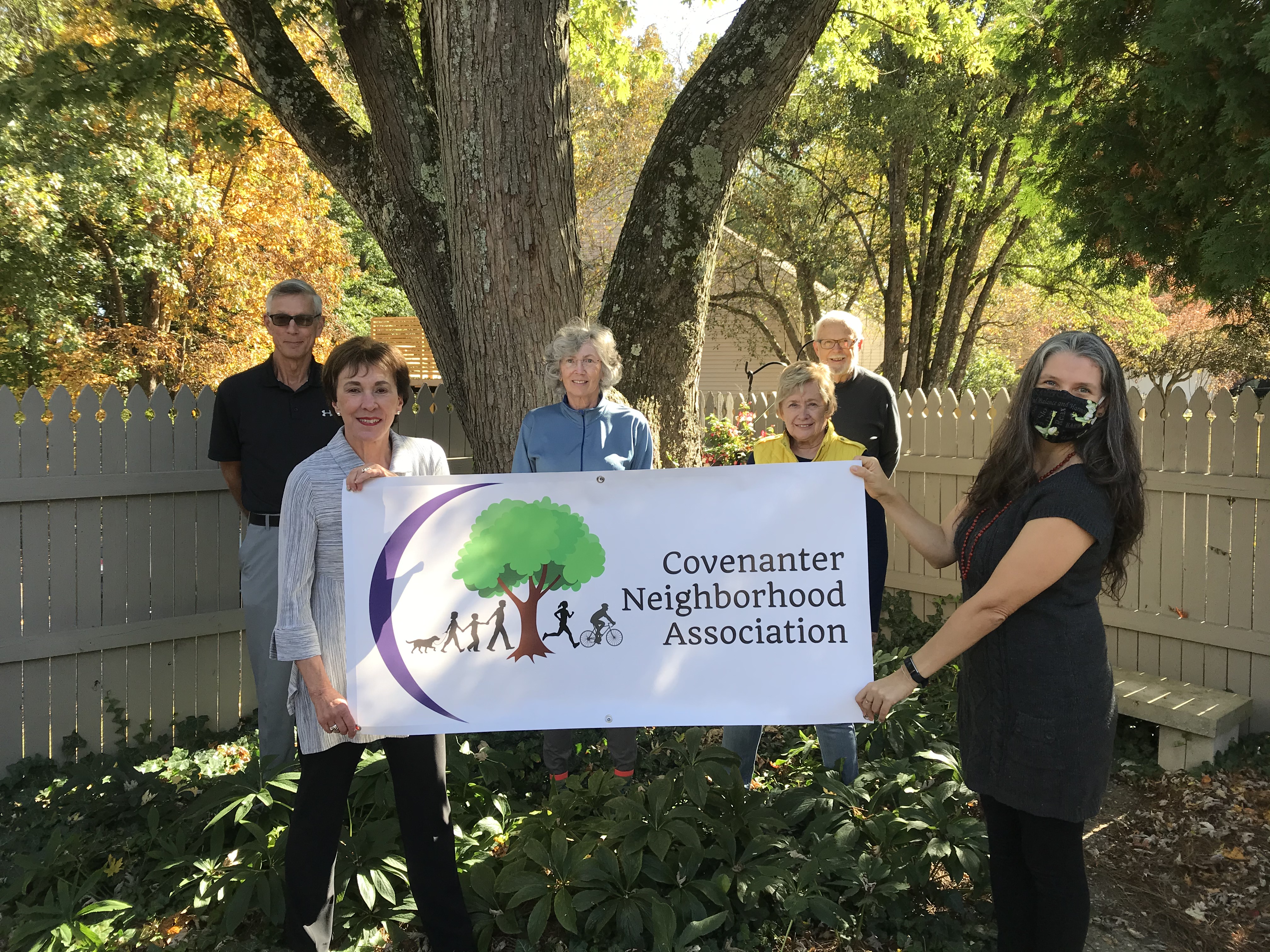 Covenanter neighbors hold a banner depicting their neighborhood association logo