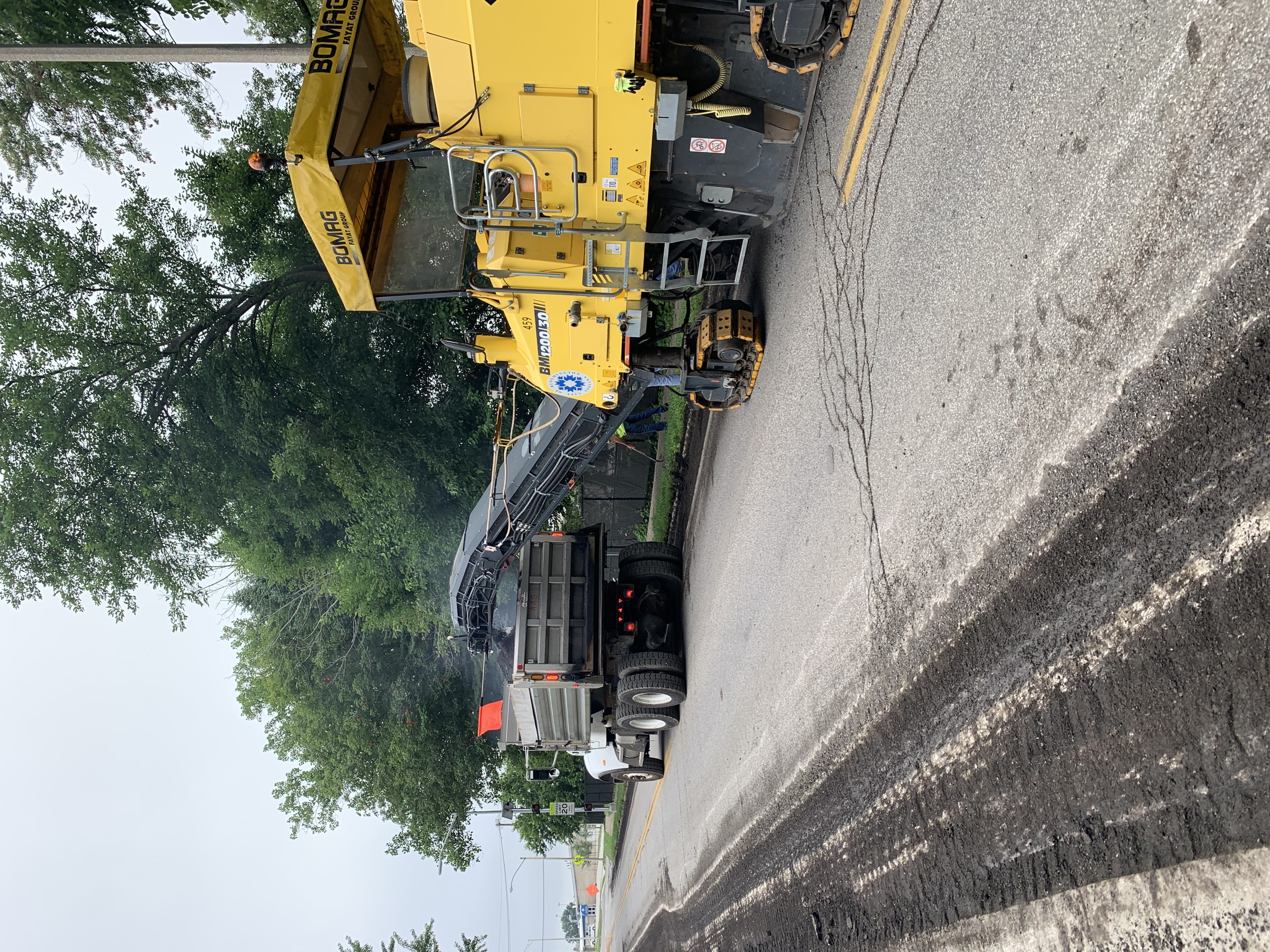 A milling machine deposits the removed road materials into a dump truck. 