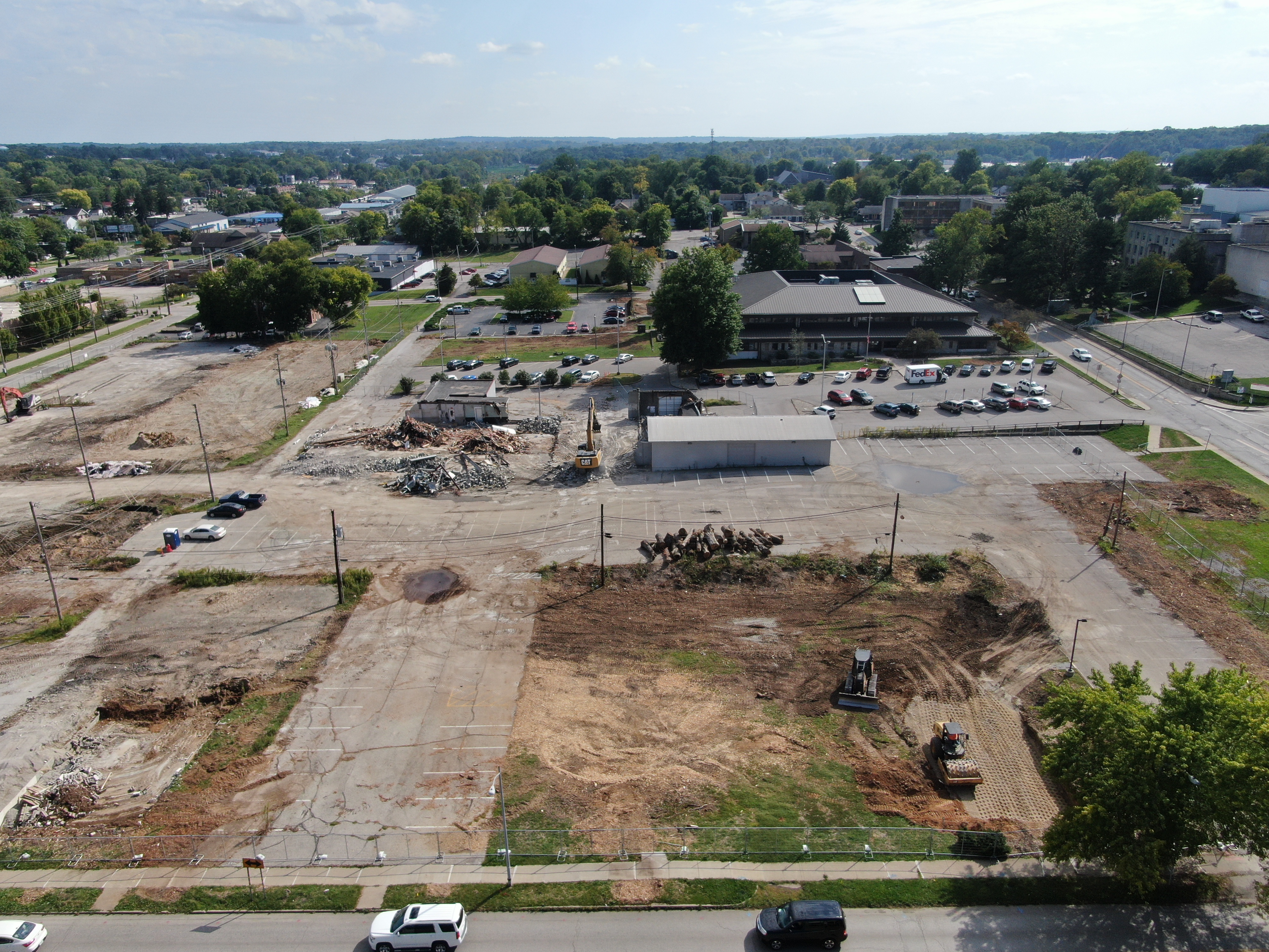 Aerial drone photo showing the development site during demolition. The left photo is looking south from the intersection of 2nd and Madison Street, there is a bulldozer and sheepsfoot roller preparing the exposed earth and an excavator demolishing a warehouse.