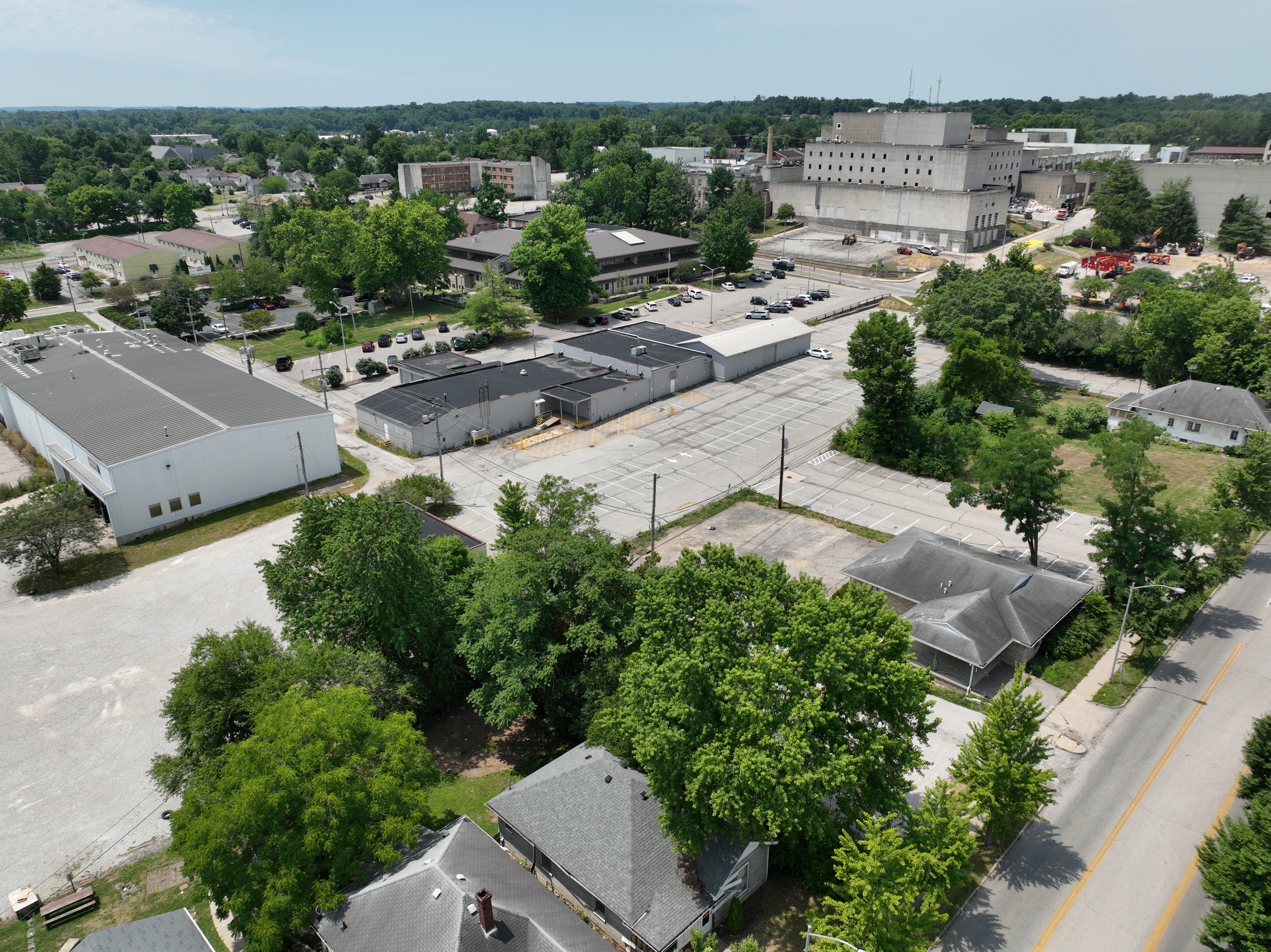 Aerial drone photo showing the development site prior to demolition. The left photo looks southwest from the intersection of 2nd and Morton Street, showing residential houses in the foreground with warehouses behind and the legacy hospital in the background. 