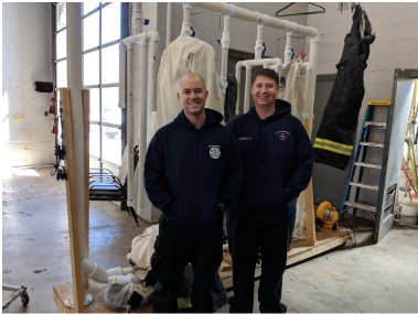 Captain Max Litwin and Engineer Robert "Bobby" McWhorter in front of the gear drying rack.