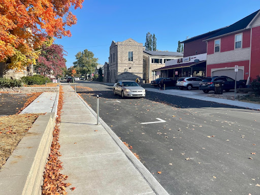 Image shows a sedan drives south on Grant between Longfei Restaurant and Soma Coffeehouse. Fall leaves line the sidewalk. 