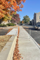Image shows a sedan drives south on Grant between Longfei Restaurant and Soma Coffeehouse. Fall leaves line the sidewalk.
